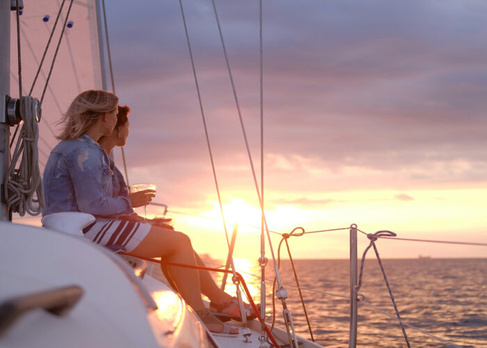 ladies-are-enjoying-their-trip-sailing-boat-while-drinking-wine-watching-beautiful-sunset-santorini